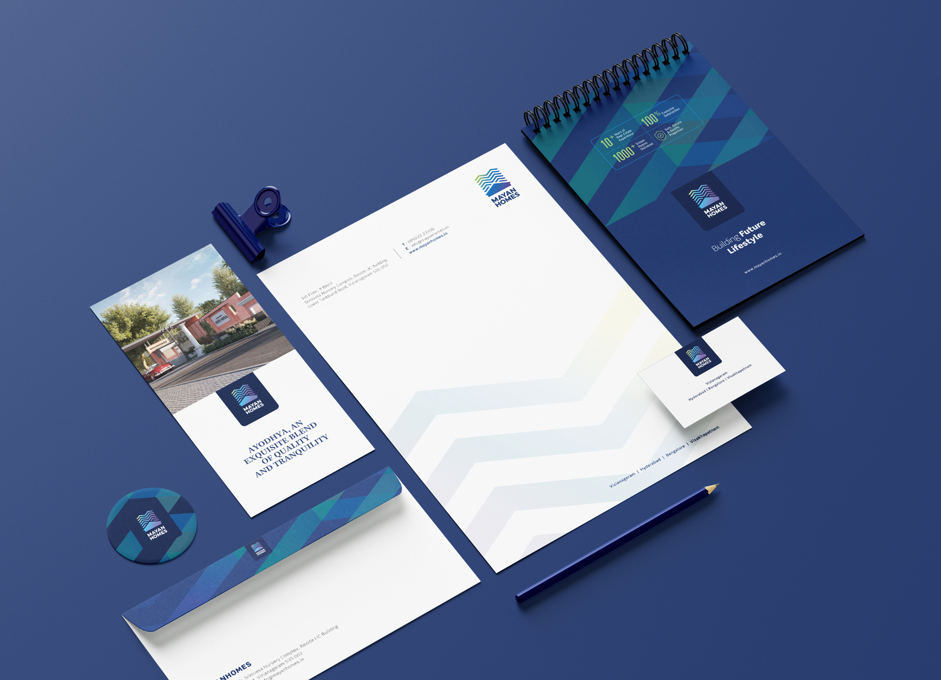 Mayan Homes real estate brand identity with brochure, letterhead, business card, and notebook design on blue background